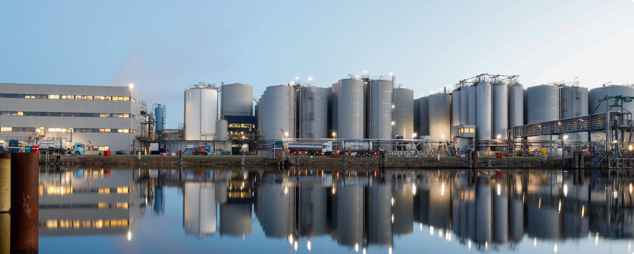 lorries parked outside large biofuel plant next to water